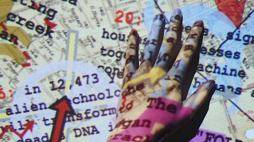 An image of a hand touching a projector screen, with the projected image on top of them both.